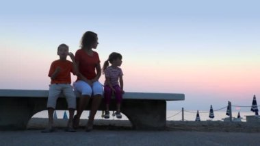 Anne ve çocuklar beach bankta oturuyor