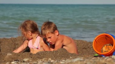 küçük kum ve kazı çukurunda oturan kız ve erkek