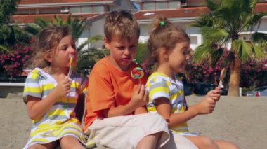 ağaç çocuklara lolipop şeker kum üzerine oturmuş yemek