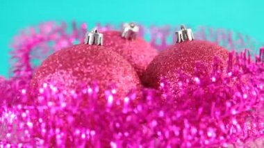 Üç pembe Noel ağacı top döndürme, mavi zemin üzerine mor tinsel çevrili
