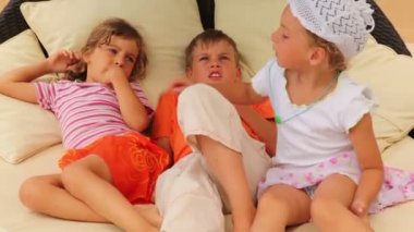 yastıklar yatakta yatan ve konuşurken üç çocuk