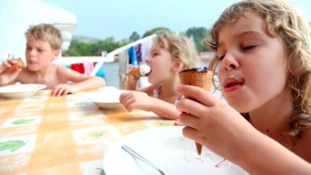 Дети сидят на балконе и едят мороженое — стоковое видео