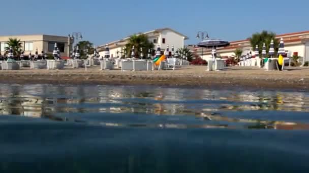 En la playa del hotel desde el agua y la cámara está en la superficie del agua — Vídeos de Stock