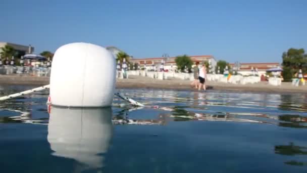 Bouée de gros plan, deux personnes sur la plage en arrière-plan — Video