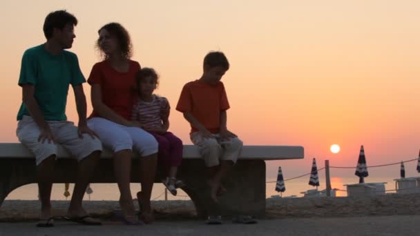 Мама, дети и папа сидят на скамейке запасных — стоковое видео