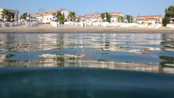 On hotel beach from water, camera is on water surface — Stock Video