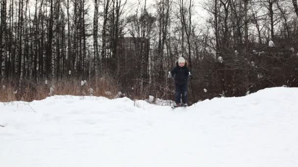 Мальчик спускается на лыжах со снежного холма — стоковое видео