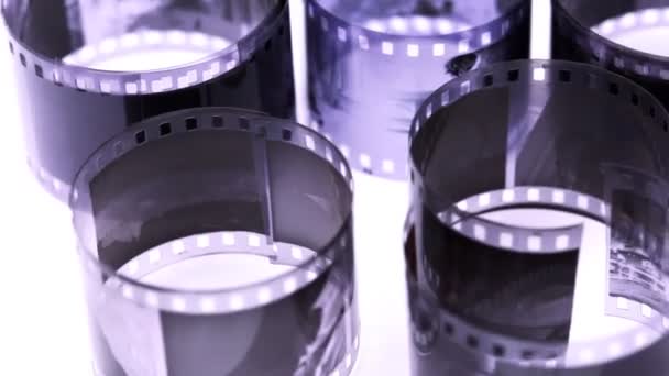 Rollos de película negativa en blanco y negro giran sobre la superficie de la luz — Vídeos de Stock