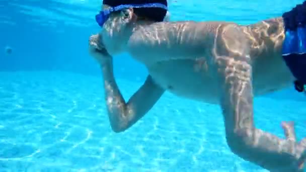 Jongen die betrekking hebben op zijn neus drijft in het zwembad onder water — Stockvideo