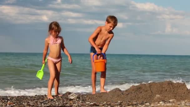 Мальчик и девочка идут к яме на песке — стоковое видео