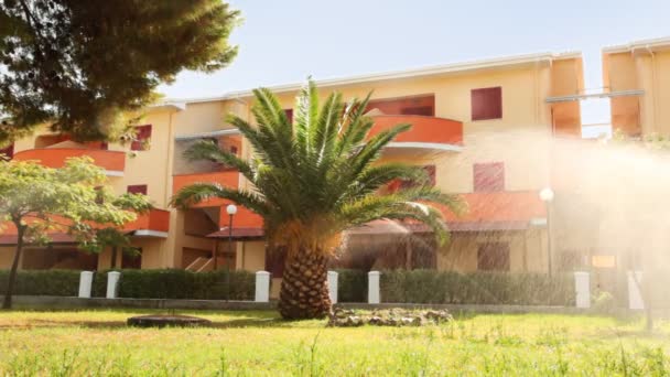 Zavlažovací systém vody palm tree a dřevo před hotel slunečný den — Stock video