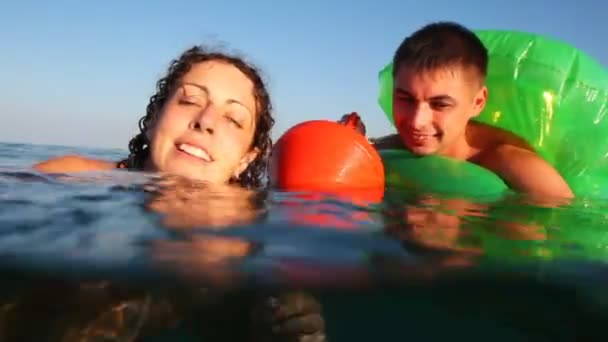 Girl and boy in inflatable disc is afraid, cannot swim, cling buoy into sea — Stock Video