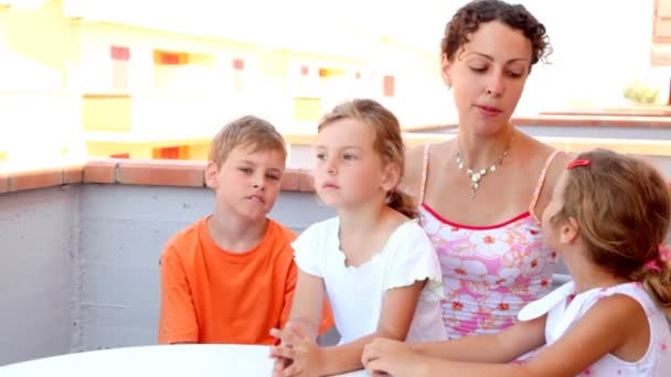 Frau und drei Kinder sitzen auf Balkon — Stockvideo