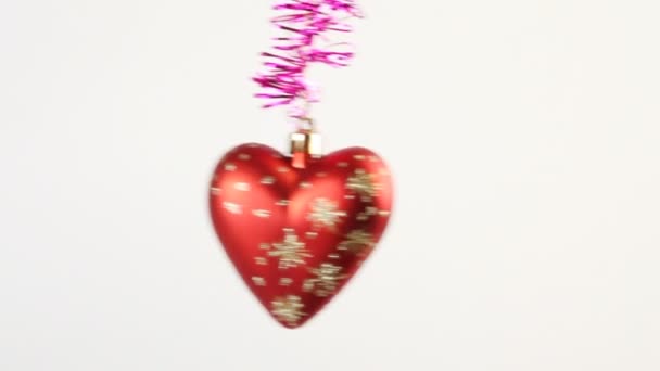 Red Christmas tree star and heart swing on purple tinsel on white — Stock Video