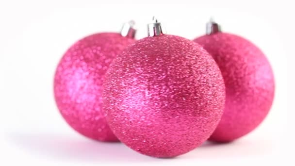 Trois boules de sapin rose noël tournent isolées sur blanc 