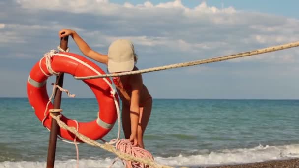 Meisje zet een touw en vormt naast reddingsboei ring — Stockvideo