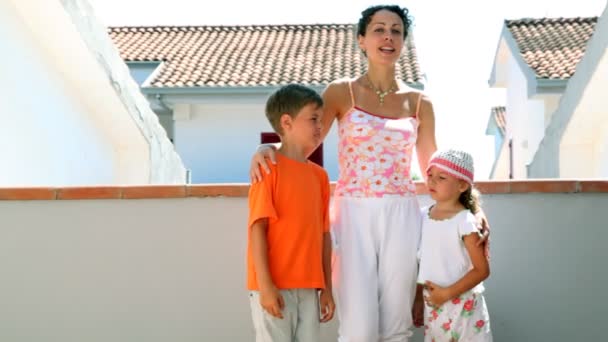Мама и двое детей стоят на балконе — стоковое видео
