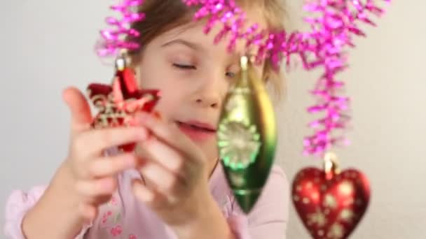 Klein meisje spelen met kerstboom decoratie, die hangen. — Stockvideo