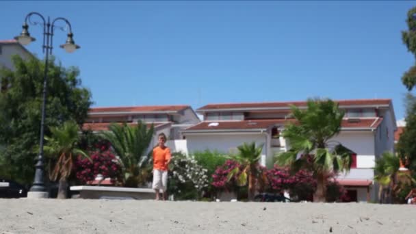 Young boy walking closer by sand street at summer — Stock Video