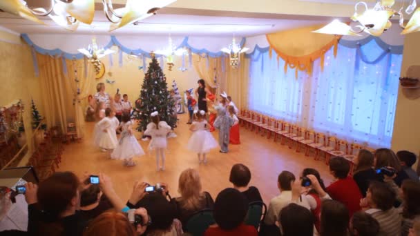 Kinder tanzen im Kindergarten um einen Tannenbaum — Stockvideo