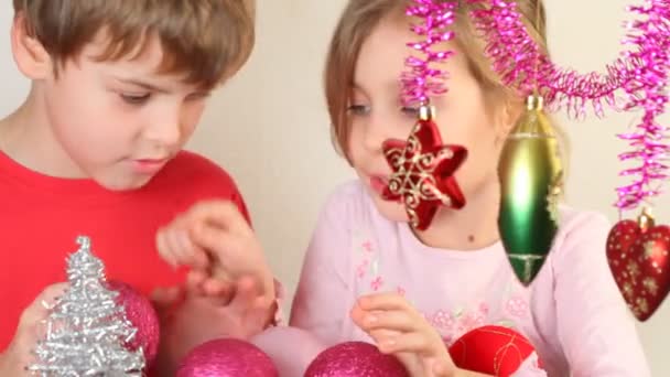 Meisje en jongen spelen met kerstboom decoratie — Stockvideo