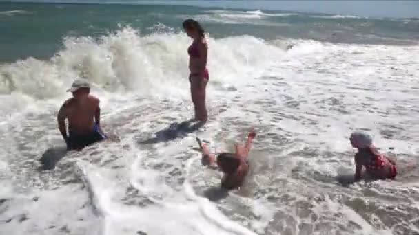 Pais e filhos a chafurdar nas ondas do mar rolou — Vídeo de Stock