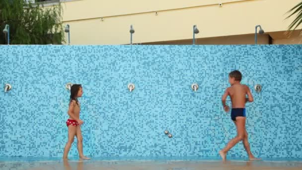 Girl with boy run along wall for showers playfully turned on and off water — Stock Video