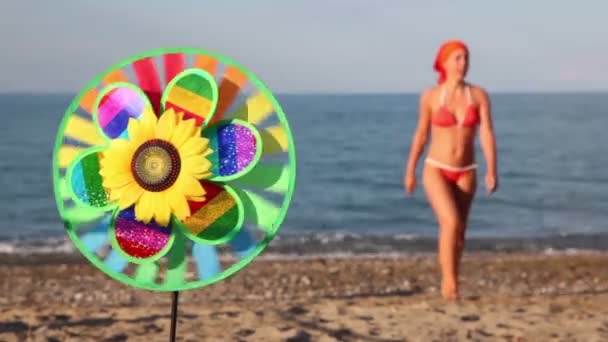 Toy with sunflower in center, that spins on the background of sea and woman — Stock Video