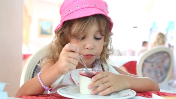 Een klein meisje eet yoghurt met jam — Stockvideo