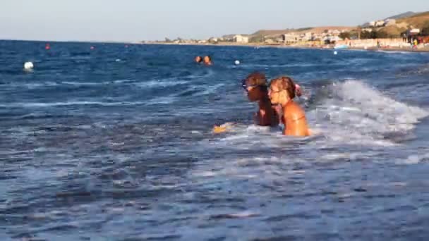 Little girl and boy play with waves at edge of sea — Stock Video