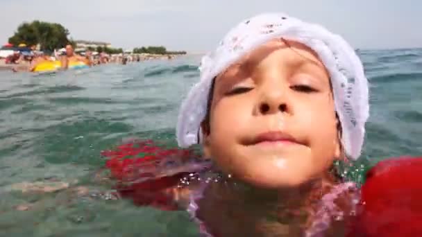 Little girl in inflatable arm ruffles swims at sea — Stock Video