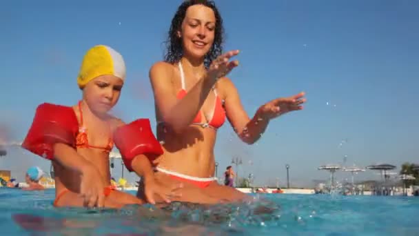 Maman avec fille assis sur la section piscines, éclaboussure d'eau — Video