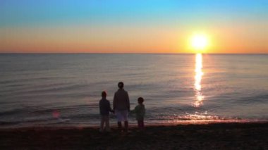 Anne ve iki çocukları sahilde duran