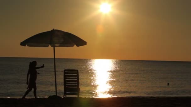 Žena prošla zleva doprava a vyrobené fotografii západu slunce na telefonu — Stock video