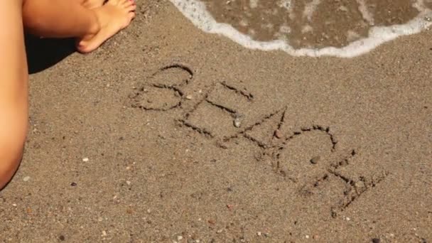 Het woord strand is geschreven op het zand, zee Golf worden weergegeven — Stockvideo