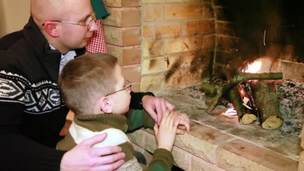 Padre e hijo sentados cerca de la chimenea — Vídeo de stock