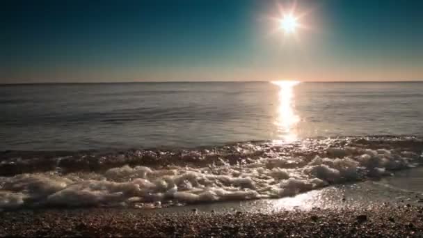 Surf myje część plaży o zachodzie słońca, słońca odzwierciedlenia w wodzie — Wideo stockowe