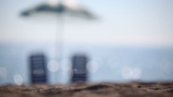 Stoją dwie puste leżaki na plaży pod parasolem — Wideo stockowe