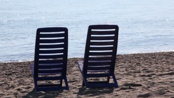 Two empty deckchairs stand on beach — Stock Video