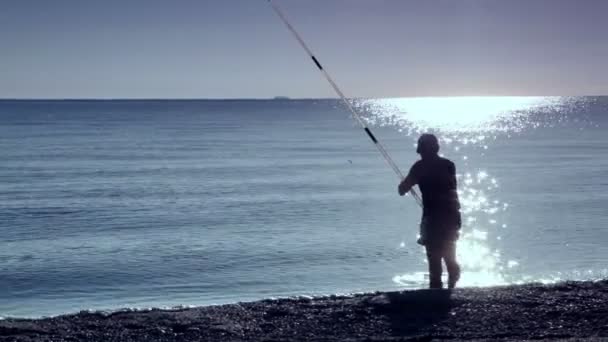 El hombre está en el agua de mar y la pesca — Vídeos de Stock