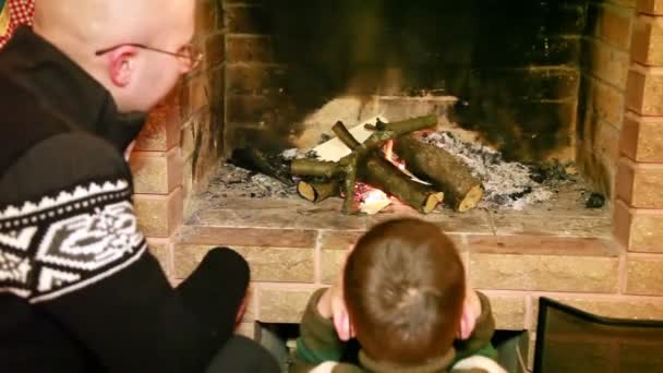 Father and son sitting by fireplace — Stock Video