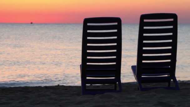 Two deckchairs stand on beach at evening — Stock Video