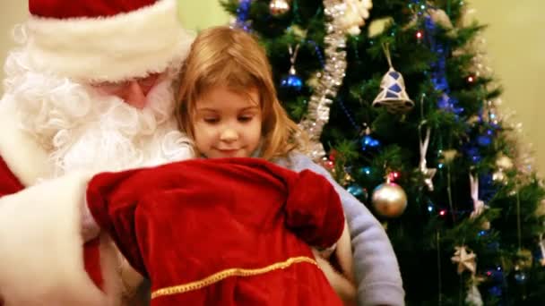 Santa Claus le da regalos a una chica cerca del árbol de Navidad — Vídeos de Stock