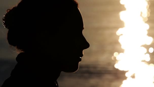 Silhouette eines Frauenkopfes mit Sonnenschein, der sich im Wasser spiegelt — Stockvideo