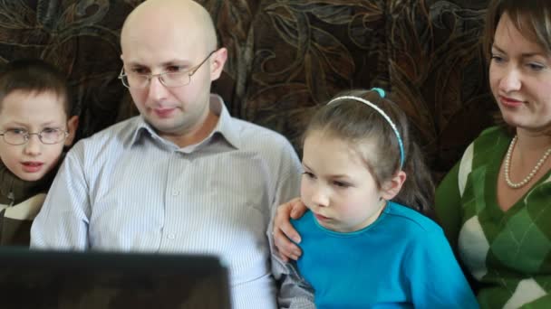 Сім'я сидить на дивані і дивиться на екран ноутбука — стокове відео