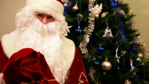 Санта-Клаус с подарками и новогодней елкой дома — стоковое видео