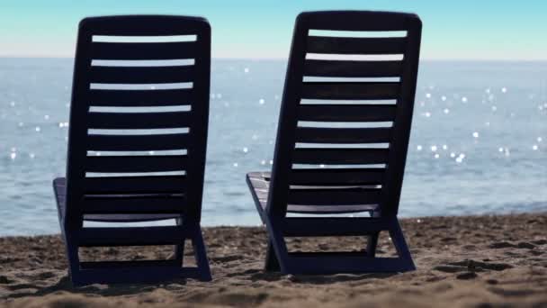 Two empty deckchairs stand on beach — Stock Video