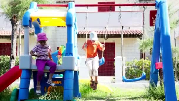 Zwei Kinder auf Spielplatz, Junge schwankt auf Schaukel Mädchen ging aus — Stockvideo