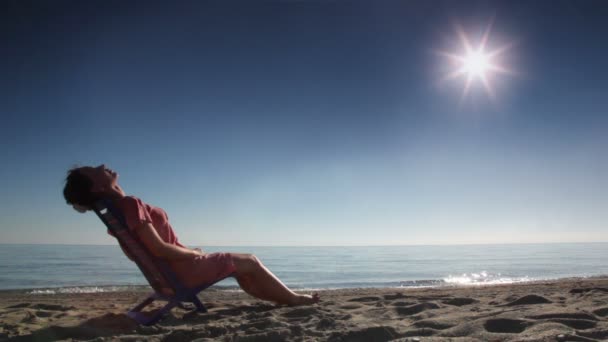 Woman leaned back on deckchair and tans — Stock Video