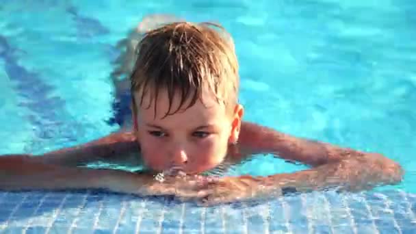 Rapaz agarra-se à borda da piscina — Vídeo de Stock